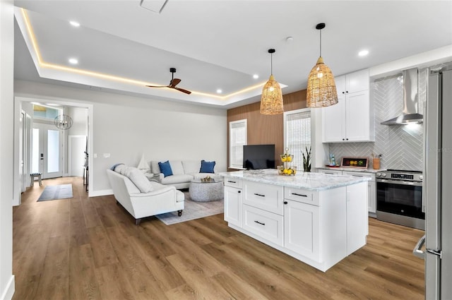 56 Columbia Ln, Palm Coast, FL 32137 - kitchen featuring wall chimney range hood, appliances with stainless steel finishes, open floor plan, white cabinets, and backsplash