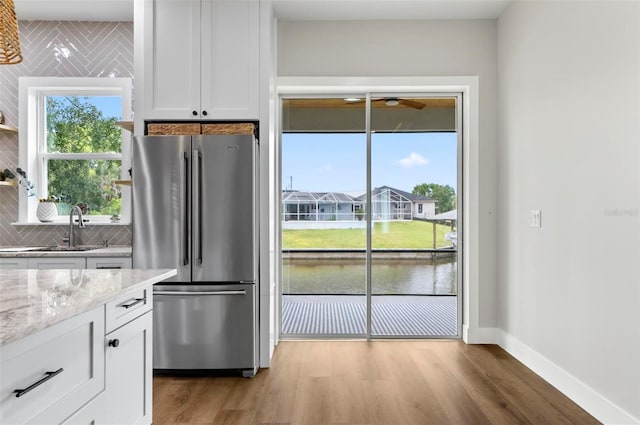 56 Columbia Ln, Palm Coast, FL 32137 - kitchen with freestanding refrigerator, decorative backsplash, white cabinets, and light wood-style flooring