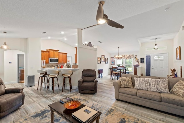 82 Ryland Dr, Palm Coast, FL 32164 - living area featuring a ceiling fan, vaulted ceiling, light wood-type flooring, arched walkways, and a chandelier