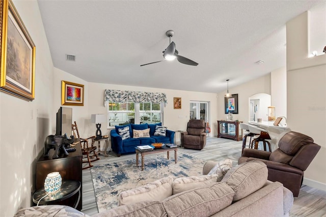 82 Ryland Dr, Palm Coast, FL 32164 - living room with arched walkways, ceiling fan, vaulted ceiling, light wood-style floors, and a textured ceiling