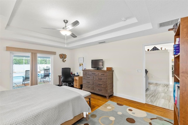 82 Ryland Dr, Palm Coast, FL 32164 - bedroom featuring a tray ceiling, access to exterior, light wood-style floors, ceiling fan, and baseboards
