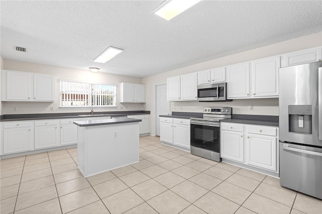 16 Flemington Ln, Palm Coast, FL 32137 - kitchen featuring appliances with stainless steel finishes, a textured ceiling, dark countertops, white cabinets, and a center island