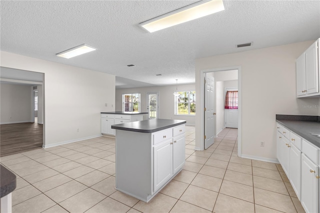 16 Flemington Ln, Palm Coast, FL 32137 - kitchen with dark countertops, a textured ceiling, light tile patterned floors, and a kitchen island