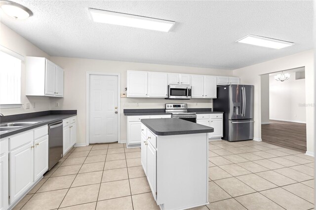 16 Flemington Ln, Palm Coast, FL 32137 - kitchen featuring appliances with stainless steel finishes, dark countertops, a textured ceiling, a center island, and white cabinetry