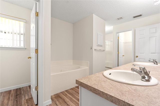 16 Flemington Ln, Palm Coast, FL 32137 - full bathroom featuring double vanity, wood finished floors, a garden tub, a textured ceiling, and baseboards