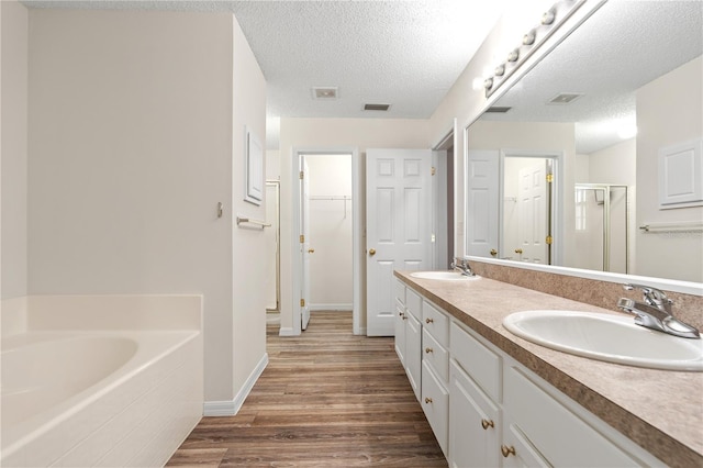 16 Flemington Ln, Palm Coast, FL 32137 - bathroom featuring wood finished floors, a shower stall, double vanity, a garden tub, and a spacious closet