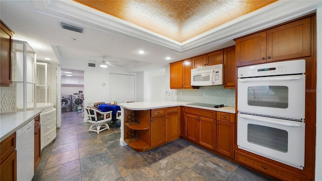 1 John Anderson Dr Unit 2180, Ormond Beach, FL 32176 - kitchen featuring white appliances, a peninsula, backsplash, washer and clothes dryer, and brown cabinetry