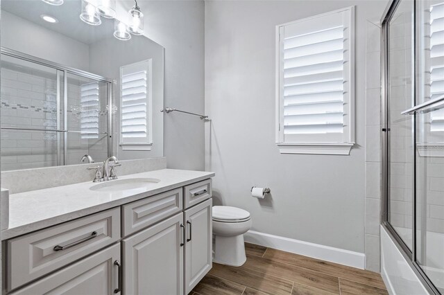 514 Wingspan Dr, Ormond Beach, FL 32174 - full bath with vanity, toilet, wood finished floors, bath / shower combo with glass door, and baseboards