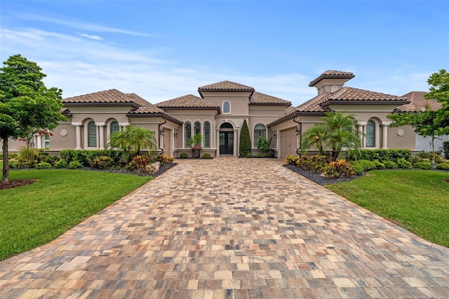 514 Wingspan Dr, Ormond Beach, FL 32174 - mediterranean / spanish house featuring decorative driveway, a garage, stucco siding, and a front lawn