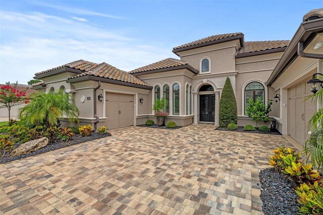 514 Wingspan Dr, Ormond Beach, FL 32174 - mediterranean / spanish house with an attached garage, decorative driveway, a tiled roof, and stucco siding