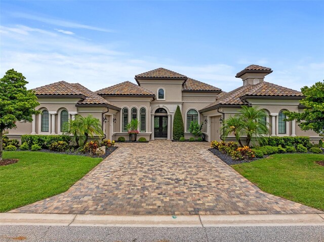 514 Wingspan Dr, Ormond Beach, FL 32174 - mediterranean / spanish house featuring stucco siding, an attached garage, decorative driveway, french doors, and a front yard