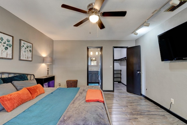 35 Whippoorwill Ln, Ormond Beach, FL 32174 - bedroom with wood finished floors, a walk in closet, ensuite bathroom, a ceiling fan, and baseboards
