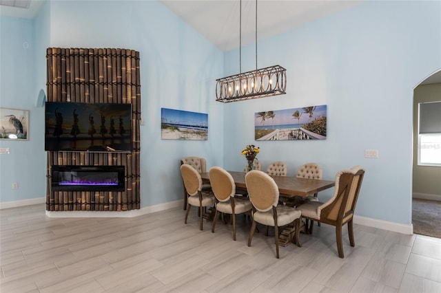 11 Tideway Trl, Palm Coast, FL 32137 - dining area with a glass covered fireplace, wood finished floors, arched walkways, baseboards, and high vaulted ceiling
