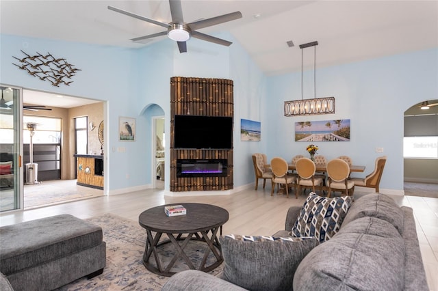 11 Tideway Trl, Palm Coast, FL 32137 - living room with arched walkways, a ceiling fan, high vaulted ceiling, a glass covered fireplace, and baseboards