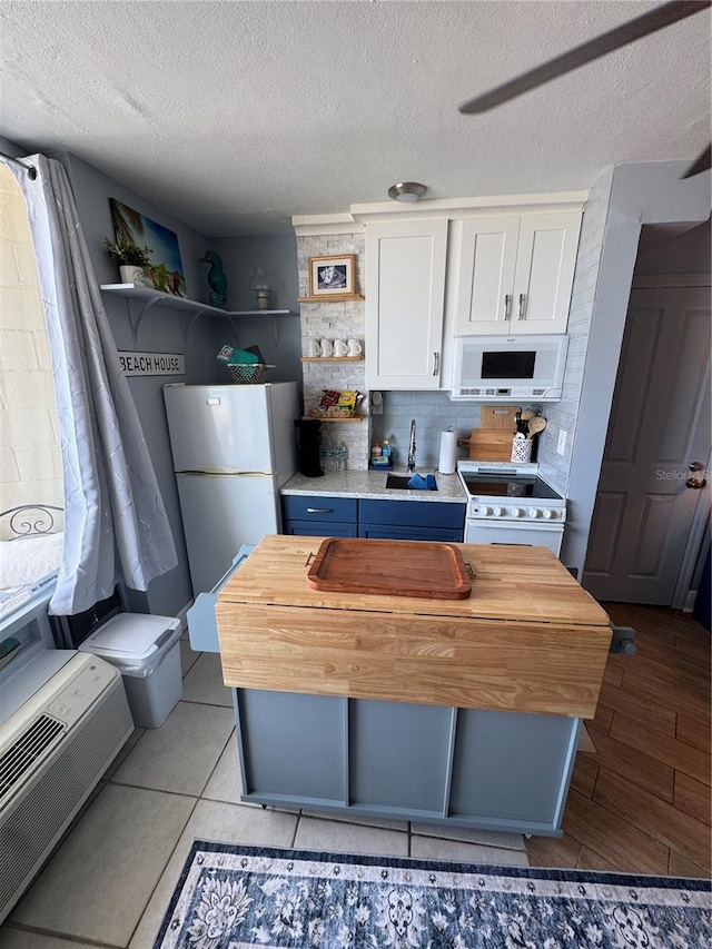 1233 S Atlantic Ave Unit 3070, Daytona Beach, FL 32118 - kitchen featuring white appliances, open shelves, white cabinetry, a textured ceiling, and wood counters
