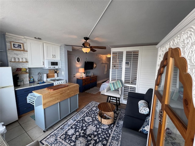 1233 S Atlantic Ave Unit 3070, Daytona Beach, FL 32118 - kitchen with white appliances, ceiling fan, blue cabinets, a textured ceiling, and wooden counters