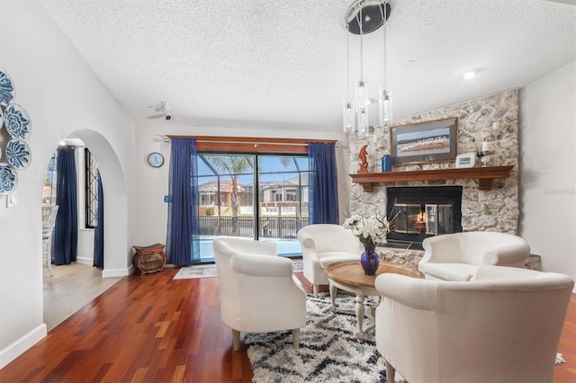 30 Clermont Ct, Palm Coast, FL 32137 - living room with a textured ceiling, arched walkways, wood finished floors, a fireplace, and baseboards
