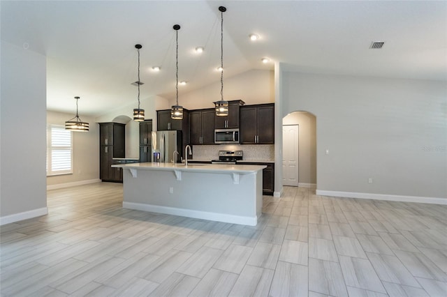 127 Wynnfield Dr, Palm Coast, FL 32164 - kitchen featuring stainless steel appliances, arched walkways, a kitchen breakfast bar, light countertops, and an island with sink