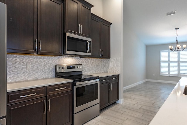 127 Wynnfield Dr, Palm Coast, FL 32164 - kitchen featuring stainless steel appliances, decorative backsplash, a chandelier, light countertops, and baseboards