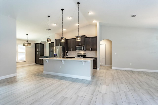 127 Wynnfield Dr, Palm Coast, FL 32164 - kitchen featuring stainless steel appliances, arched walkways, a breakfast bar area, light countertops, and a center island with sink