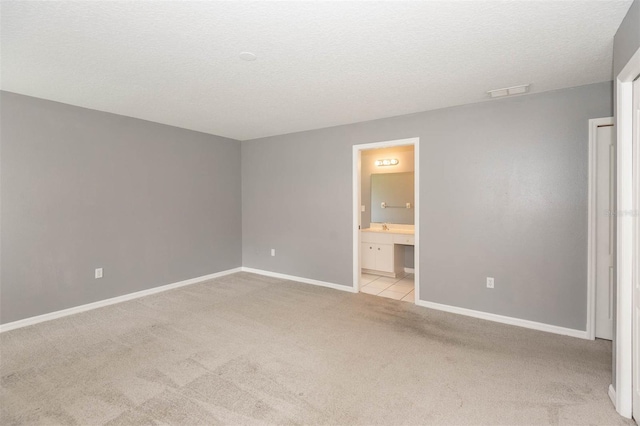 88 Pritchard Dr, Palm Coast, FL 32164 - unfurnished bedroom featuring light colored carpet, a textured ceiling, and connected bathroom