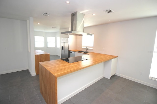 19 Cedarfield Ct, Palm Coast, FL 32137 - kitchen with appliances with stainless steel finishes, island exhaust hood, butcher block counters, baseboards, and a peninsula