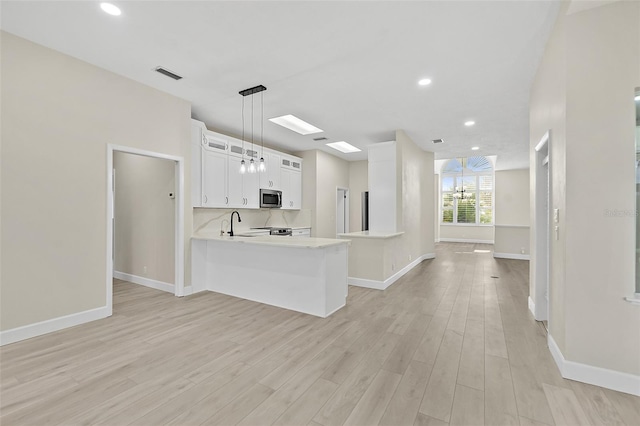 38 Kingsley Cir, Ormond Beach, FL 32174 - kitchen with appliances with stainless steel finishes, a peninsula, light wood-style flooring, light countertops, and white cabinets