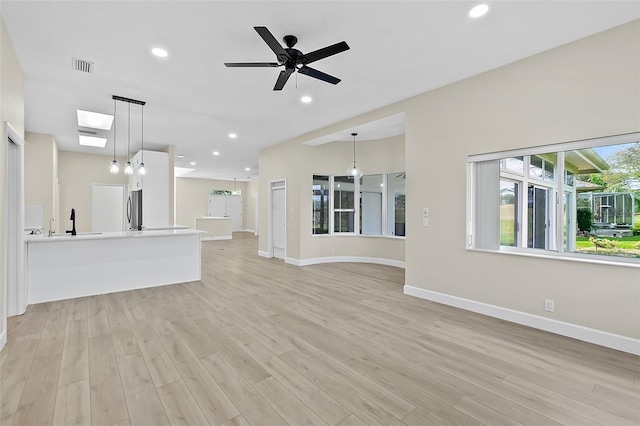 38 Kingsley Cir, Ormond Beach, FL 32174 - unfurnished living room with baseboards, light wood-style floors, a skylight, a ceiling fan, and recessed lighting