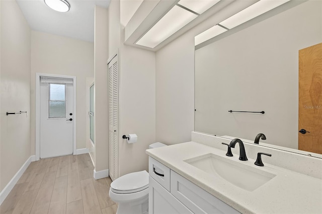 38 Kingsley Cir, Ormond Beach, FL 32174 - full bath featuring toilet, vanity, baseboards, and wood finished floors
