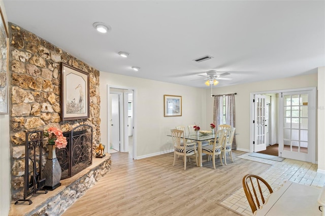 179 Frankford Ln, Palm Coast, FL 32137 - dining room with french doors, baseboards, light wood finished floors, a stone fireplace, and ceiling fan