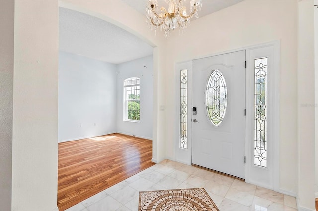 42 Raintree Pl, Palm Coast, FL 32164 - entrance foyer with arched walkways, a chandelier, tile patterned flooring, and baseboards