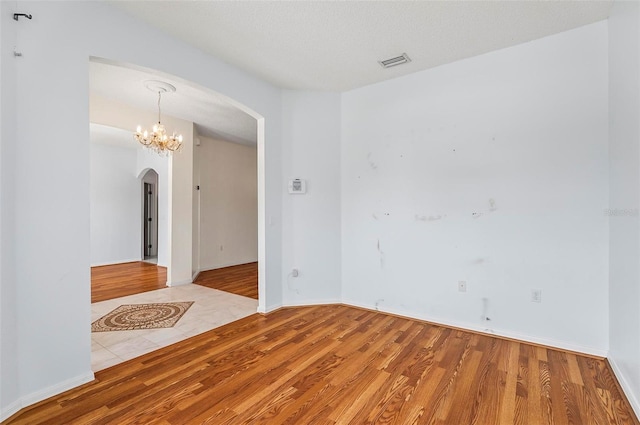 42 Raintree Pl, Palm Coast, FL 32164 - unfurnished room featuring arched walkways, wood finished floors, a chandelier, and baseboards
