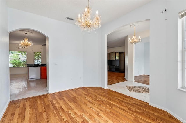 42 Raintree Pl, Palm Coast, FL 32164 - unfurnished room with a chandelier, arched walkways, and light wood-style flooring