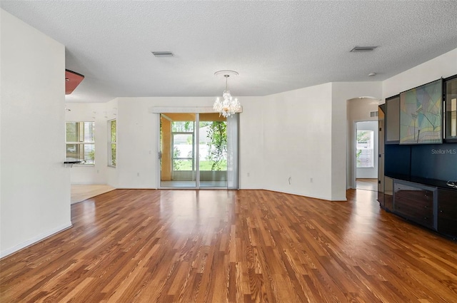 42 Raintree Pl, Palm Coast, FL 32164 - unfurnished living room featuring wood finished floors, a chandelier, arched walkways, and a textured ceiling
