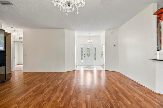 42 Raintree Pl, Palm Coast, FL 32164 - unfurnished living room featuring a chandelier, wood finished floors, a textured ceiling, and baseboards