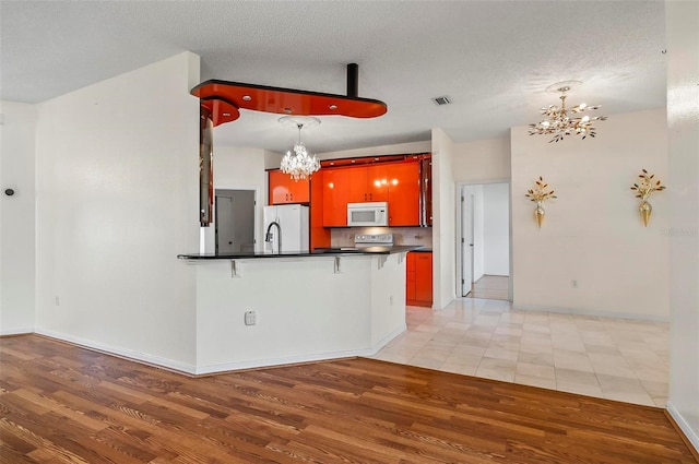 42 Raintree Pl, Palm Coast, FL 32164 - kitchen featuring white microwave, refrigerator with ice dispenser, a chandelier, dark countertops, and light wood finished floors