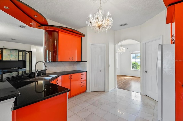 42 Raintree Pl, Palm Coast, FL 32164 - kitchen with freestanding refrigerator, a chandelier, a sink, arched walkways, and dark countertops