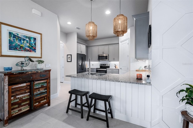 17 Newhaven Ln, Ormond Beach, FL 32174 - kitchen featuring appliances with stainless steel finishes, gray cabinetry, light stone counters, a peninsula, and decorative light fixtures