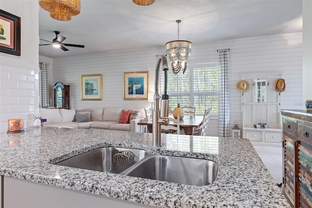 17 Newhaven Ln, Ormond Beach, FL 32174 - kitchen featuring a chandelier, ceiling fan, light stone counters, open floor plan, and hanging light fixtures