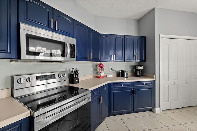 4 Seathorn Path, Palm Coast, FL 32164 - kitchen featuring appliances with stainless steel finishes, blue cabinetry, light countertops, light tile patterned floors, and a textured ceiling