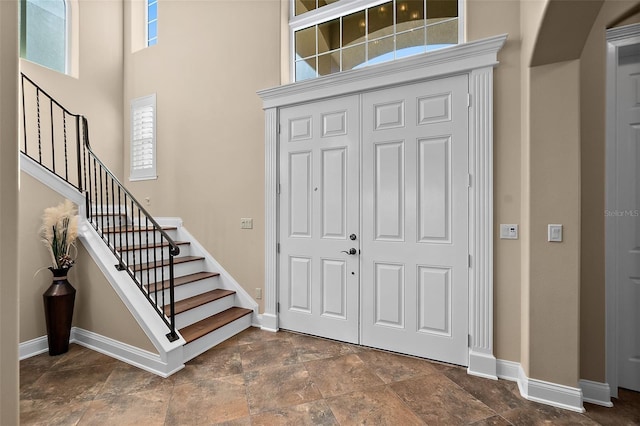 207 S Riverwalk Dr, Palm Coast, FL 32137 - entryway featuring a towering ceiling, stone finish floors, stairway, and arched walkways