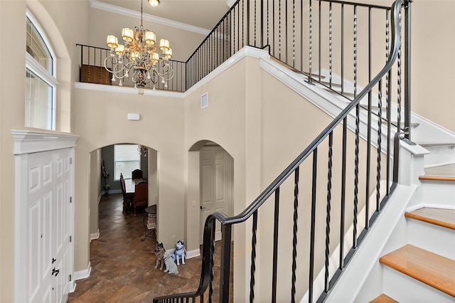 207 S Riverwalk Dr, Palm Coast, FL 32137 - entryway featuring arched walkways, crown molding, a chandelier, stairway, and a towering ceiling