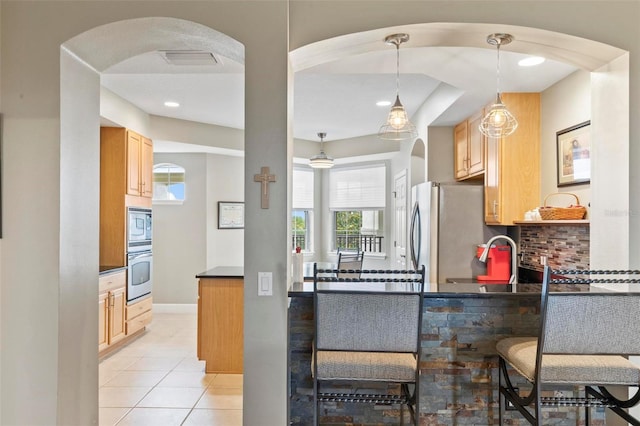 200 Riverfront Dr Unit D302, Palm Coast, FL 32137 - kitchen with appliances with stainless steel finishes, dark countertops, arched walkways, light tile patterned flooring, and recessed lighting