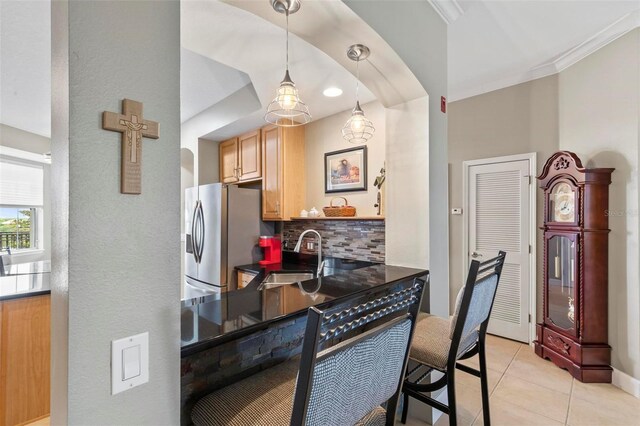 200 Riverfront Dr Unit D302, Palm Coast, FL 32137 - kitchen with stainless steel refrigerator with ice dispenser, tasteful backsplash, dark countertops, light tile patterned floors, and arched walkways