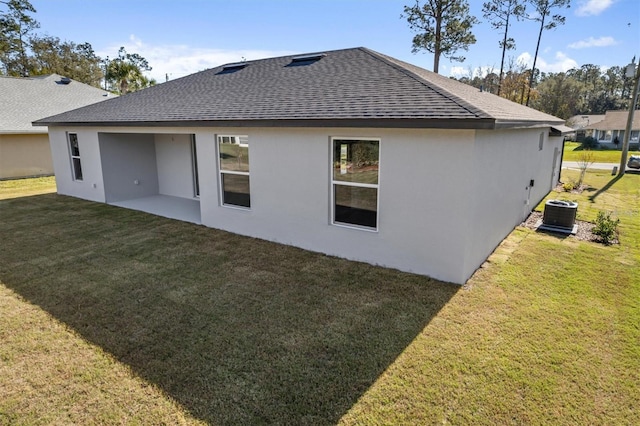 2 Seamanship Trl, Palm Coast, FL 32164 - back of property featuring a shingled roof, stucco siding, a lawn, and central AC unit