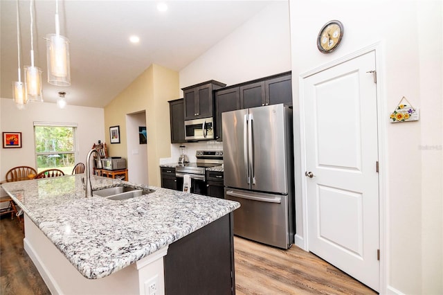 15 Raleigh Dr, Palm Coast, FL 32164 - kitchen featuring stainless steel appliances, lofted ceiling, an island with sink, light wood-style flooring, and light stone counters