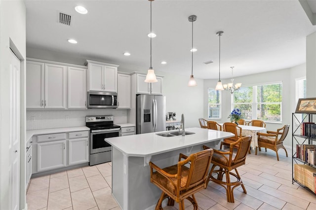 9 Port Royal Dr, Palm Coast, FL 32164 - kitchen with appliances with stainless steel finishes, light countertops, an island with sink, a chandelier, and a kitchen bar