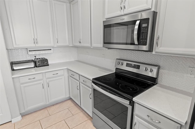 9 Port Royal Dr, Palm Coast, FL 32164 - kitchen featuring appliances with stainless steel finishes, light countertops, tasteful backsplash, white cabinetry, and light tile patterned floors