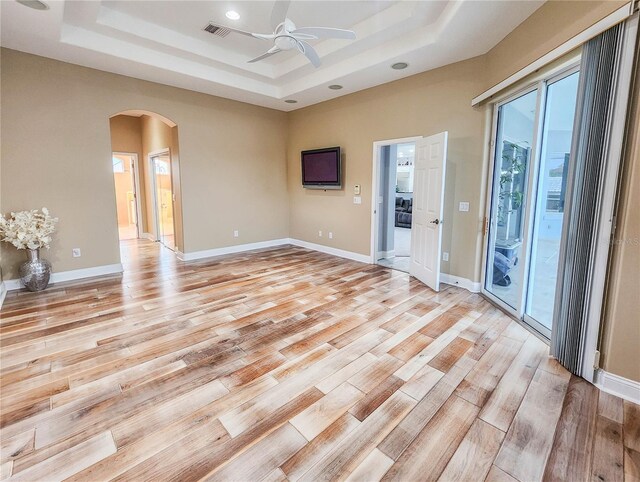 101 Covington Ln, Palm Coast, FL 32137 - spare room featuring a raised ceiling, arched walkways, ceiling fan, light wood-style flooring, and baseboards
