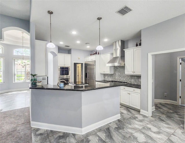 101 Covington Ln, Palm Coast, FL 32137 - kitchen featuring wall chimney range hood, appliances with stainless steel finishes, arched walkways, dark countertops, and decorative backsplash